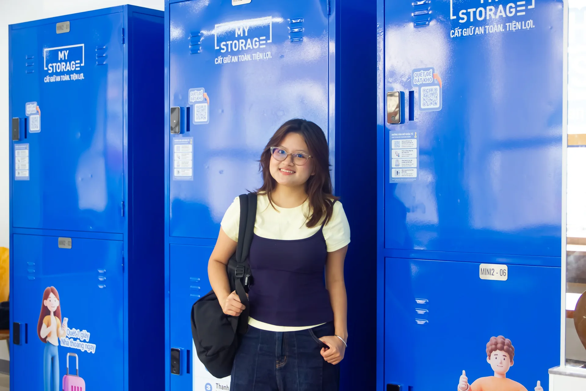 A smiling customer waving between rows of MyStorage lockers at Ministop Tran Khac Chan
