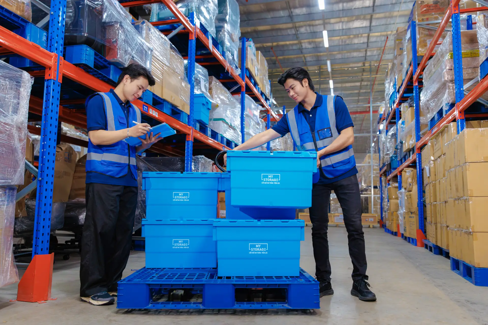 MyStorage staff pushing blue storage boxes on a trolley