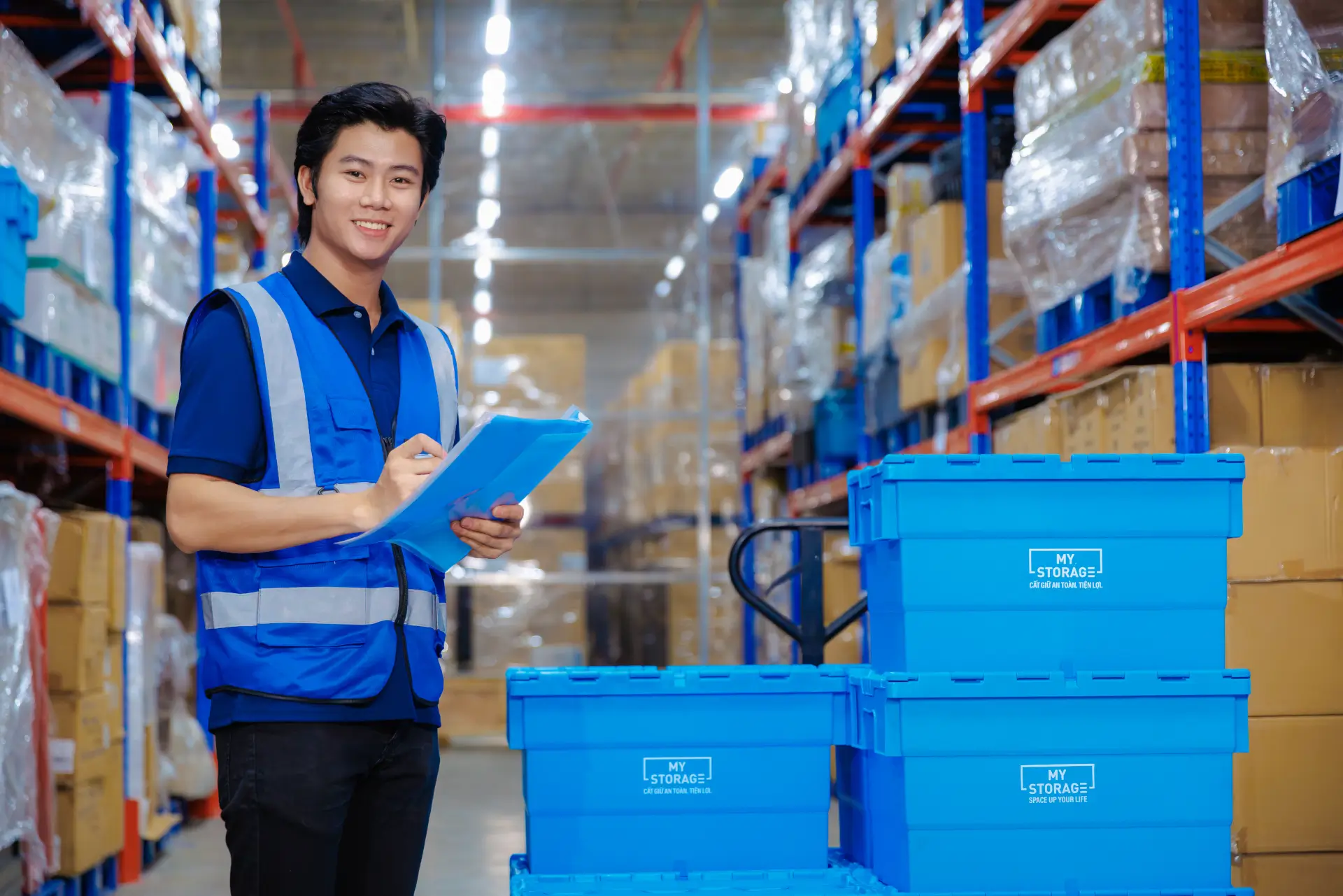MyStorage staff pushing blue storage boxes on a trolley