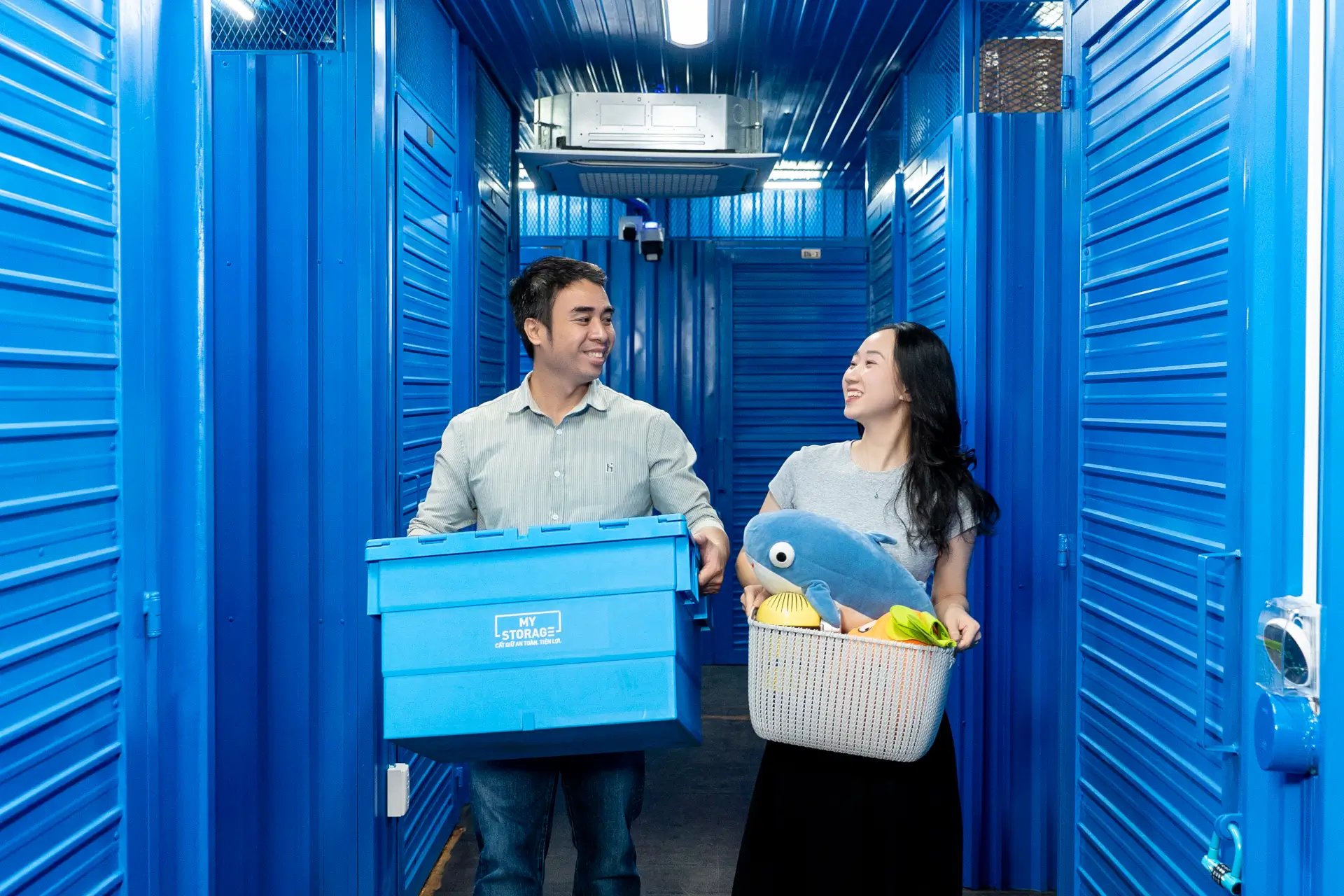 A man and a woman carrying storage items