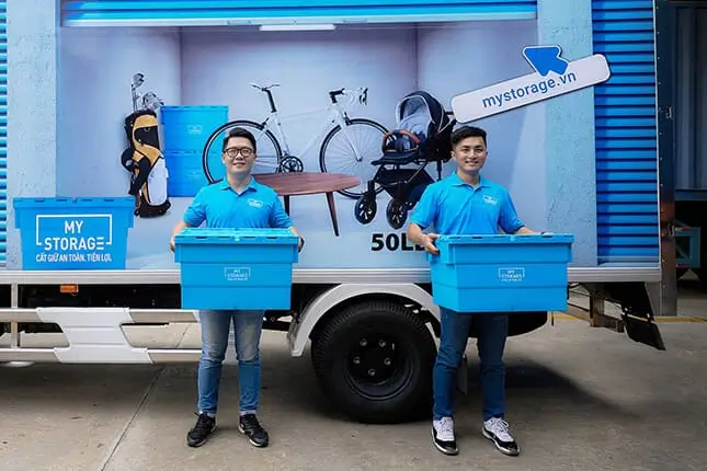 Two men carrying storage boxes at a MyStorage facility