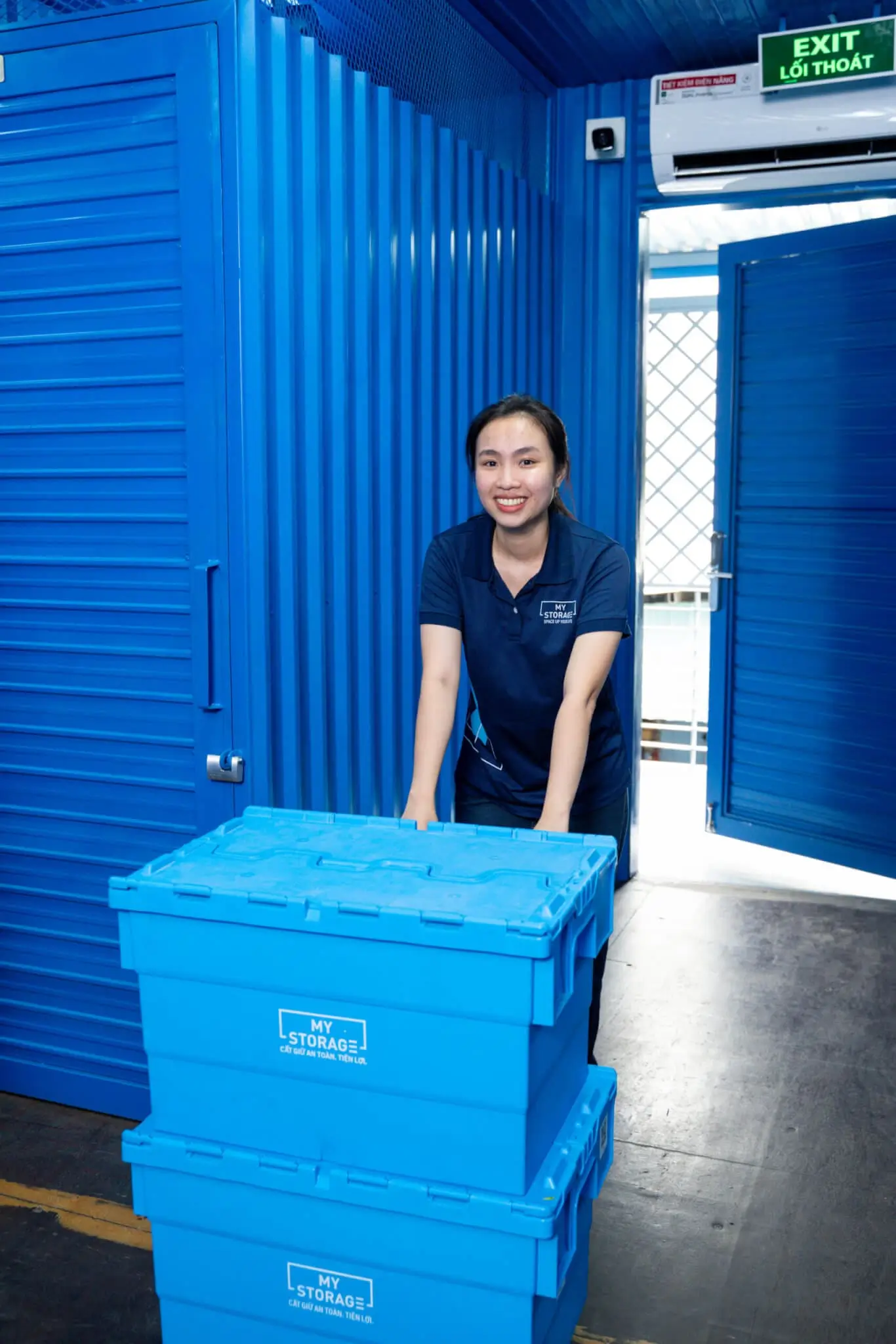 MyStorage staff member with stacked blue storage boxes