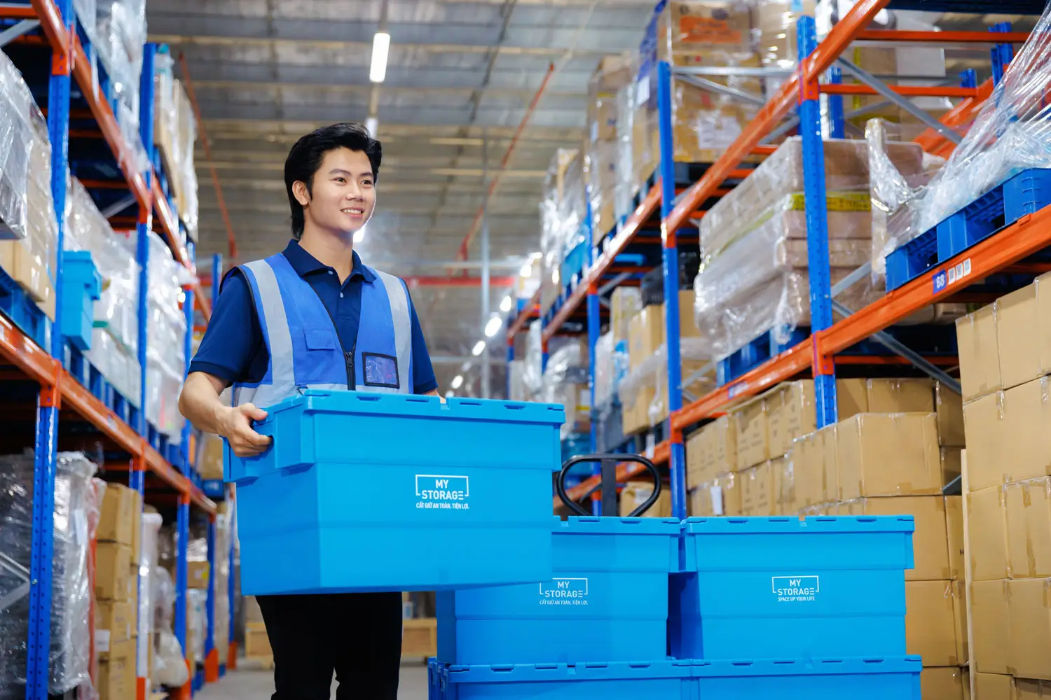 Warehouse worker carrying a blue storage box.