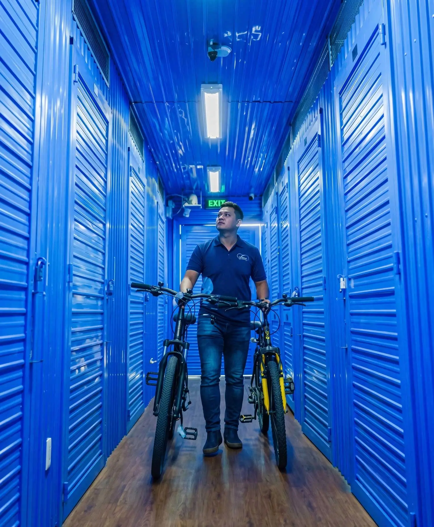 MyStorage staff member walking two bicycles down a storage unit corridor.