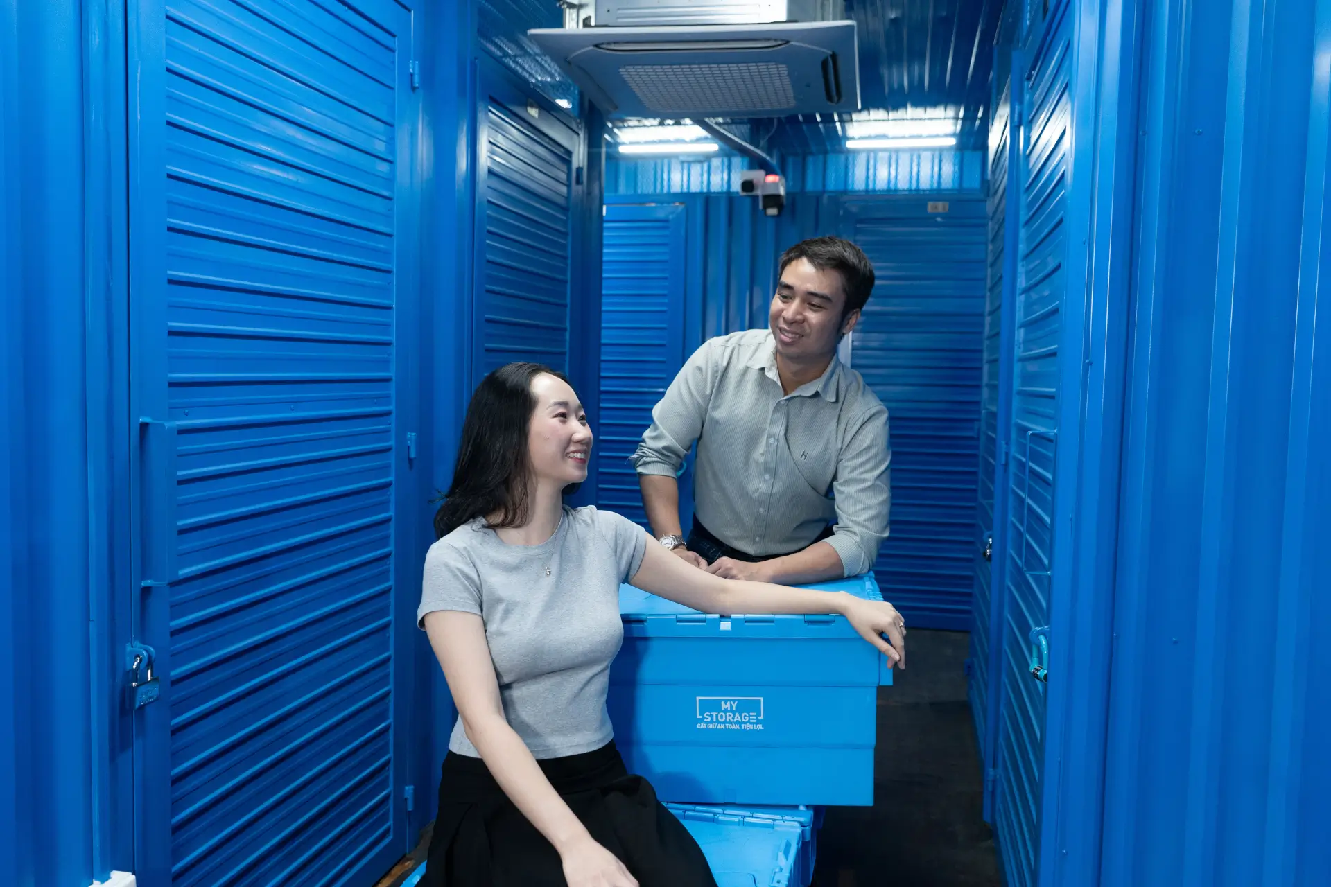 Two customers with a MyStorage crate between rows of private storage units