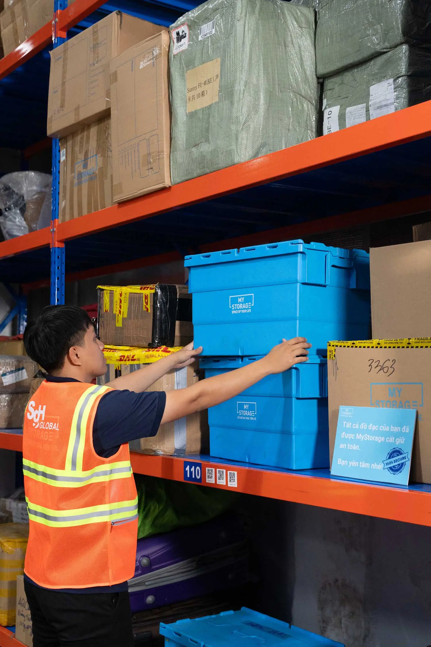 Warehouse worker placing blue storage containers on a shelf