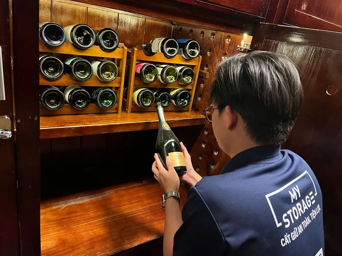 MyStorage staff holding a wine bottle in the wine storage room